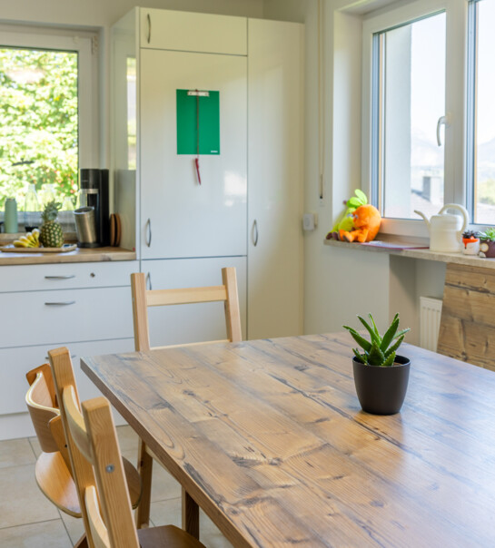 Besprechungstisch aus Holz mit Blick zu Küchenfront und Fenster
