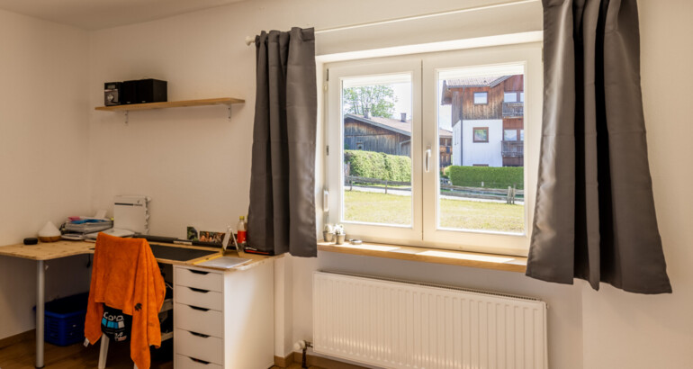 Innenansicht eines Zimmers der Wohngemeinschaft mit Schreibtisch und Blick in den Garten.