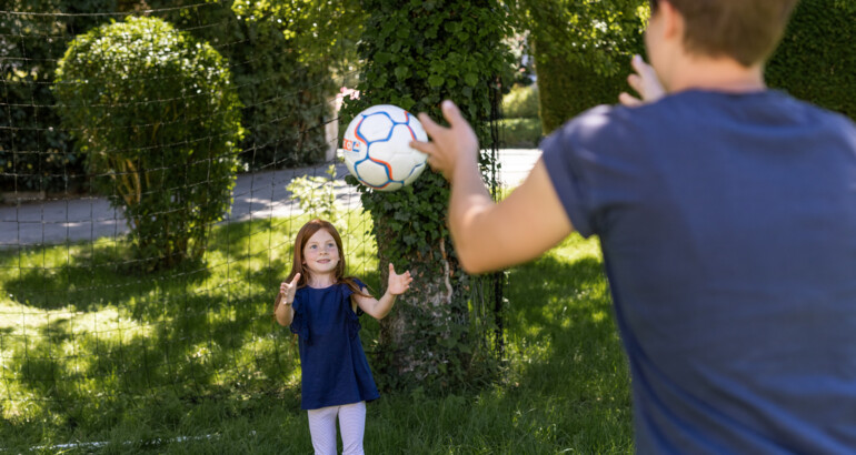 Sozialpädagogin wirft einen Ball spielerisch zu einem Mädchen