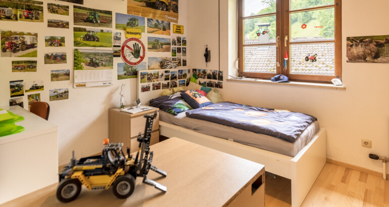 Innenansicht eines Schlafzimmers der Wohngemeinschaft mit Bett, Regal, Schreibtisch und eine Lego-Figur.