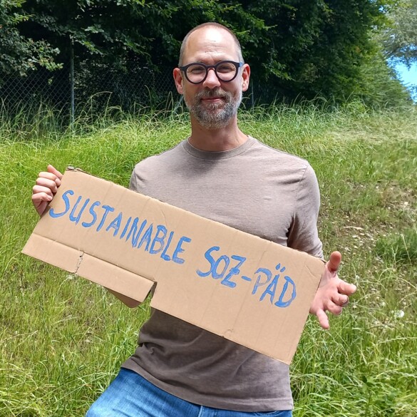 Nachhaltigkeitsbeauftragter Andreas Trummer hält ein Schild mit der Aufschrift "Sustainable Soz-Päd"