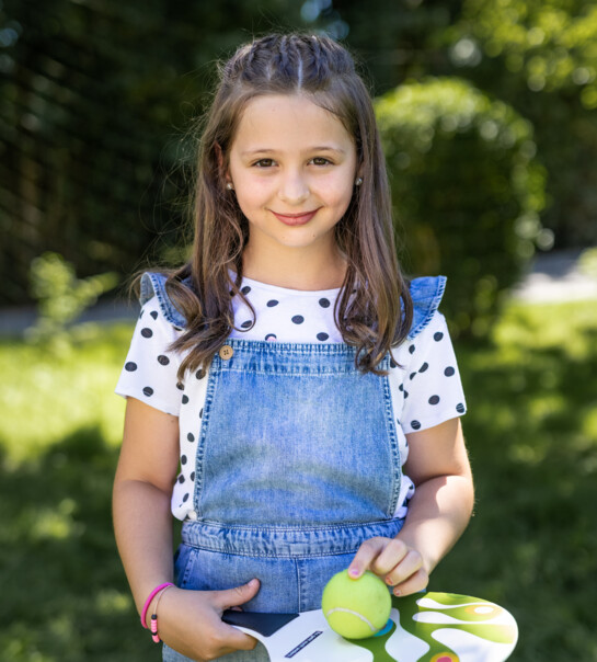 Portrait von einem Kind, welches einen Tischtennis Schläger mit Ball hält.